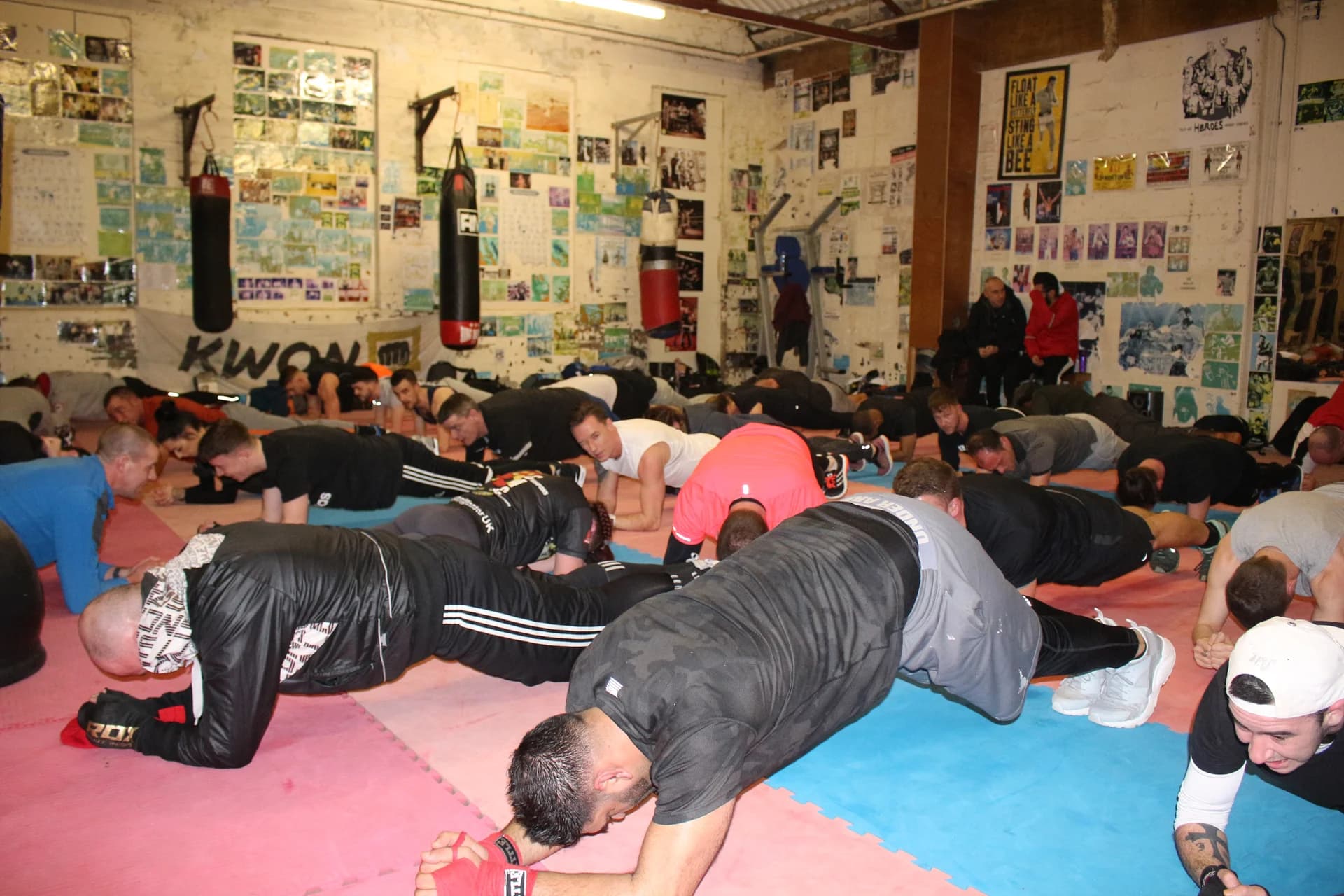 A group holding forearm planks on the red and blue mats at UFCC